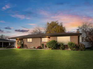 View of front of property featuring brick siding, a front yard, and a chimney