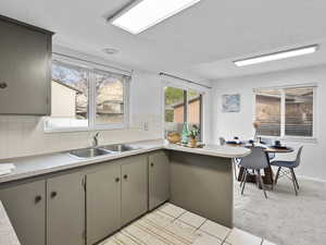 Kitchen with decorative backsplash, light countertops, a peninsula, light tile patterned floors, and plenty of natural light