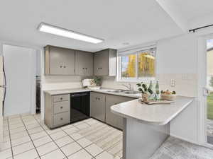 Kitchen featuring a peninsula, tasteful backsplash, black dishwasher, and light countertops