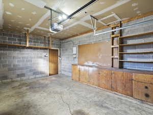Garage featuring concrete block wall and a garage door opener