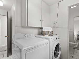 Laundry room with light tile patterned flooring, washer and dryer, and cabinet space