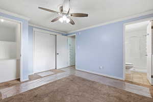 Unfurnished bedroom with crown molding, a textured ceiling, ceiling fan, a closet, and connected bathroom