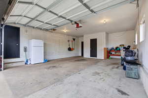 Garage featuring freestanding refrigerator and a garage door opener