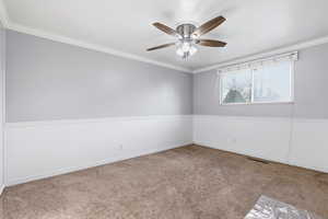 Carpeted spare room featuring ornamental molding and ceiling fan