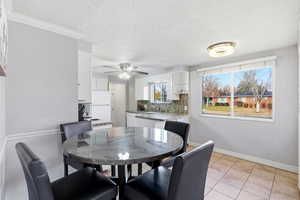 Dining space featuring a textured ceiling, light tile patterned flooring, and a ceiling fan