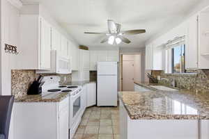 Kitchen featuring white appliances, white cabinetry, light stone counters, a textured ceiling, and backsplash