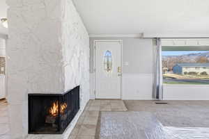 Entrance foyer with light tile patterned floors, a textured ceiling, a fireplace, and light carpet