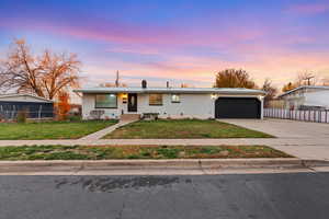View of front facade featuring a metal roof, concrete driveway, brick siding, and a garage