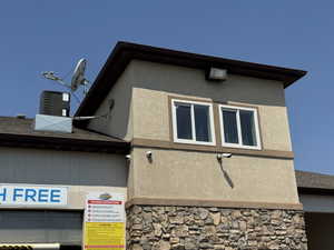 View of side of property featuring stone siding, stucco siding, and roof with shingles