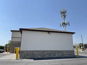 View of side of home featuring roof with shingles and stone siding
