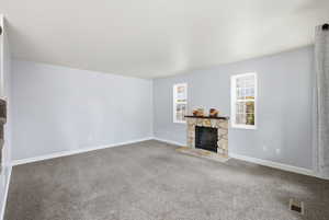 Unfurnished living room featuring a fireplace and carpet floors