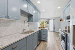 Kitchen with light stone countertops, stainless steel appliances, recessed lighting, light wood-style floors, and backsplash