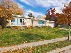 View of front of property featuring brick siding, a front yard, an attached garage, and driveway