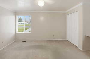 Unfurnished bedroom with carpet floors, ornamental molding, and a closet