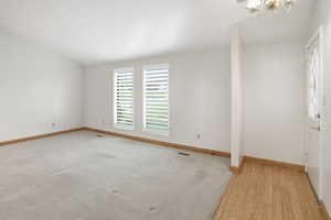 Unfurnished room featuring a chandelier and baseboards