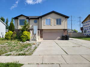 Split foyer home featuring brick siding, driveway, and a garage