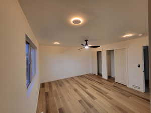 Unfurnished bedroom with multiple closets, light wood-type flooring, and ceiling fan