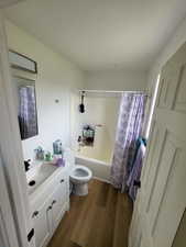 Bathroom featuring vanity, shower / bath combo with shower curtain, and dark wood finished floors