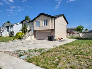 Bi-level home featuring an attached garage, brick siding, concrete driveway, and a residential view
