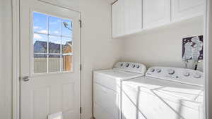 Washroom featuring separate washer and dryer and cabinet space