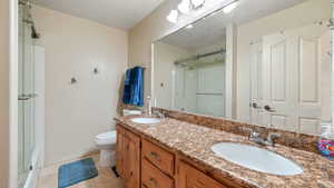 Bathroom with double vanity, a shower stall, and light tile patterned floors