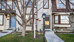 Doorway to property featuring stone siding, stucco siding, and a lawn
