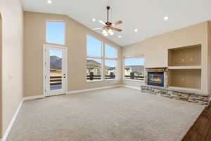 Unfurnished living room with high vaulted ceiling, a fireplace, built in shelves, ceiling fan, and carpet