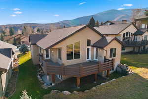View of front of property featuring a deck with mountain view, a front yard, stucco siding, and a residential view