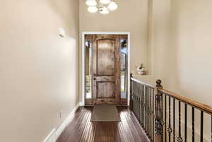 Entrance foyer with dark wood-style flooring and a chandelier