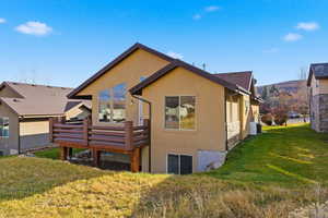 Rear view of house featuring a lawn, stucco siding, and a deck with mountain view