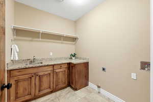 Laundry room with hookup for an electric dryer, light tile patterned floors, and cabinet space