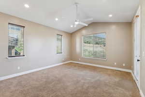 Carpeted empty room featuring vaulted ceiling, a ceiling fan, and recessed lighting
