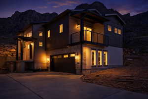 Contemporary home with a garage, driveway, stone siding, a mountain view, and a balcony