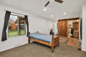 Carpeted bedroom with a barn door, recessed lighting, and a ceiling fan