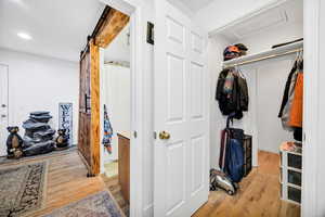 Hallway featuring a barn door, light wood-style flooring, and recessed lighting