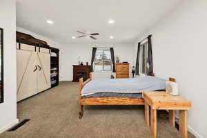 Bedroom featuring carpet flooring, ceiling fan, recessed lighting, a barn door, and a fireplace