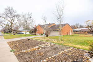 View of front facade featuring brick siding, a chimney, concrete driveway, and a garage