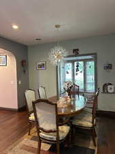 Dining room featuring arched walkways, dark wood-type flooring, recessed lighting, and a chandelier