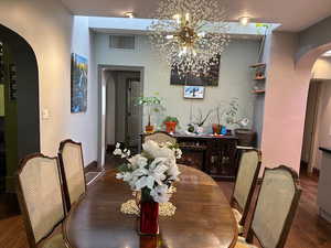Dining area with arched walkways and wood finished floors