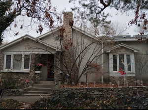 View of front of home with a chimney and stone siding