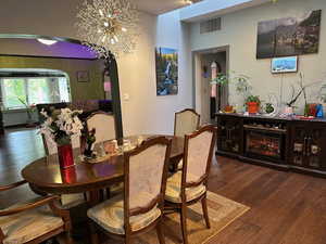 Dining room with arched walkways, dark wood-type flooring, and a chandelier