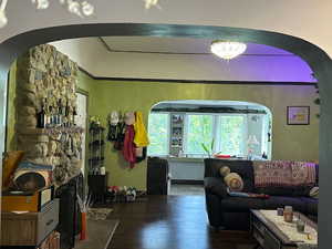 Living area with arched walkways and hardwood / wood-style floors