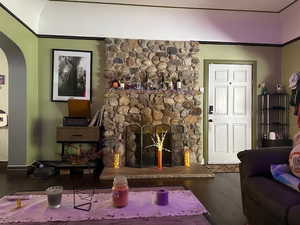 Living room with dark wood-style floors, a stone fireplace, and arched walkways