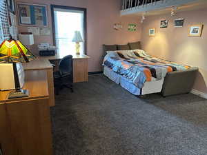 Bedroom featuring dark colored carpet and a desk