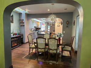 Dining room featuring dark wood-style floors, arched walkways, a chandelier, and recessed lighting