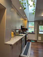 Kitchen with light stone countertops, dark wood-style floors, stainless steel appliances, recessed lighting, and a skylight