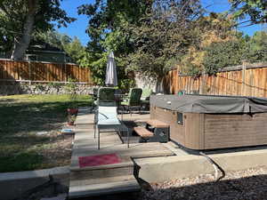 Fenced backyard featuring a deck, a hot tub, and outdoor dining space