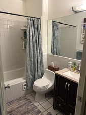 Bathroom featuring vanity, light tile patterned floors, tiled shower / bath, and tile walls
