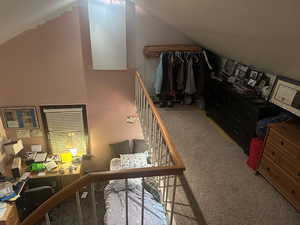 Bedroom with vaulted ceiling, light colored carpet, and an office area