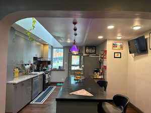 Kitchen with refrigerator, hanging light fixtures, dark wood-style floors, dishwasher, and dark stone counters